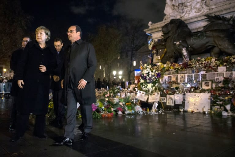 French President Francois Hollande (2L) and German Chancellor Angela Merkel (L) pay their respects to the victims of the Paris attacks on November 25, 2015, on the Place de la Republic in Paris, where they each left a white rose