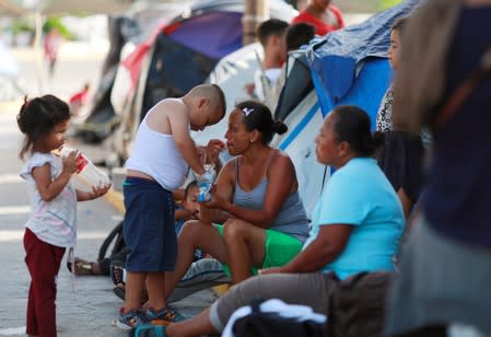 Central American migrants are seen sitting outside their tents in an encampment in Matamoros