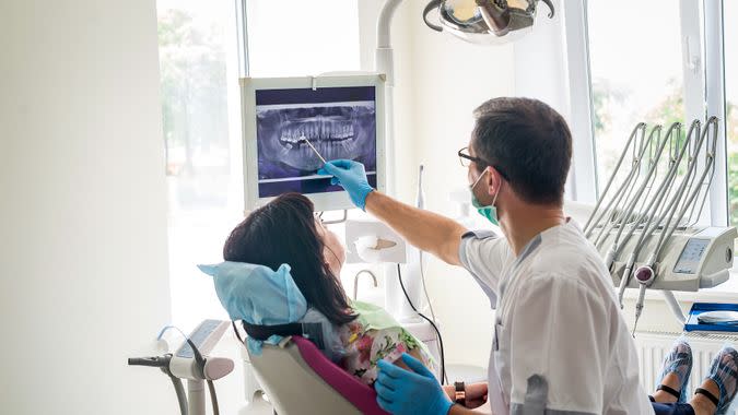 Doctor dentist showing patient's teeth on X-ray.