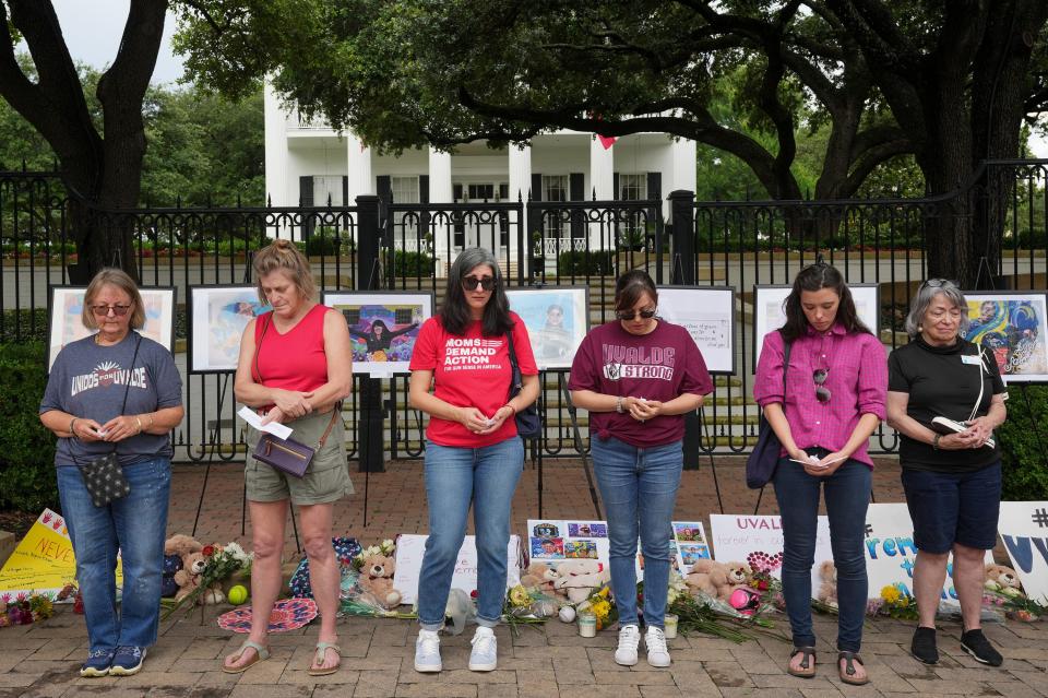 People observe a moment of silence Wednesday in front of the Governor’s Mansion at a memorial for the victims of the Uvalde school shooting. Dozens of people gathered to remember the children and teachers on the one-year anniversary of the mass shooting.