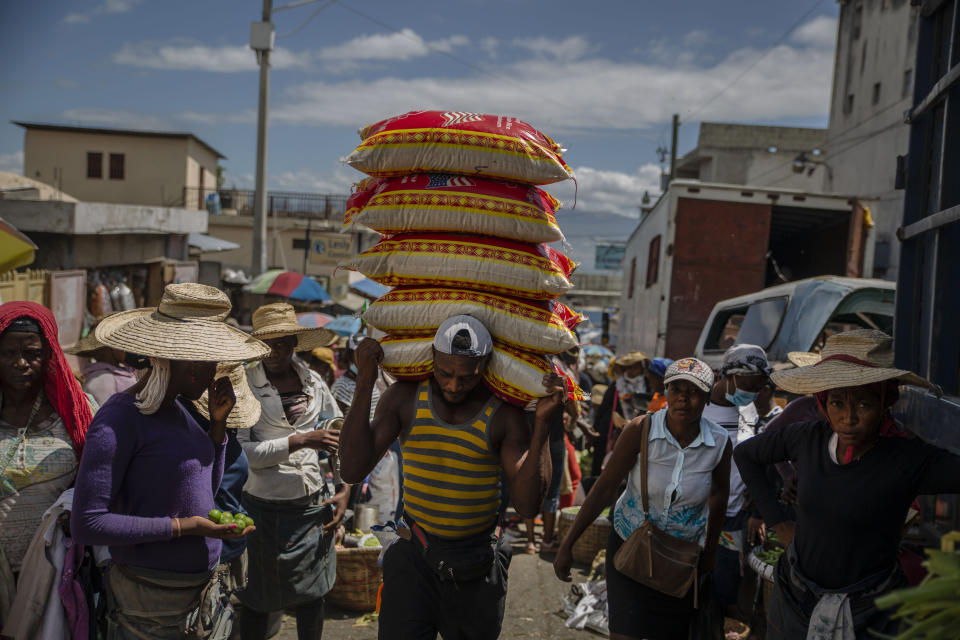 A man carries goods at a street market in Port-au-Prince, Haiti, Saturday, June 5, 2021. Haiti defied predictions and perplexed health officials by avoiding a COVID-19 crisis for more than a year, but the country of more than 11 million people that has not received a single vaccine is now battling a spike in cases and deaths. (AP Photo/Joseph Odelyn)