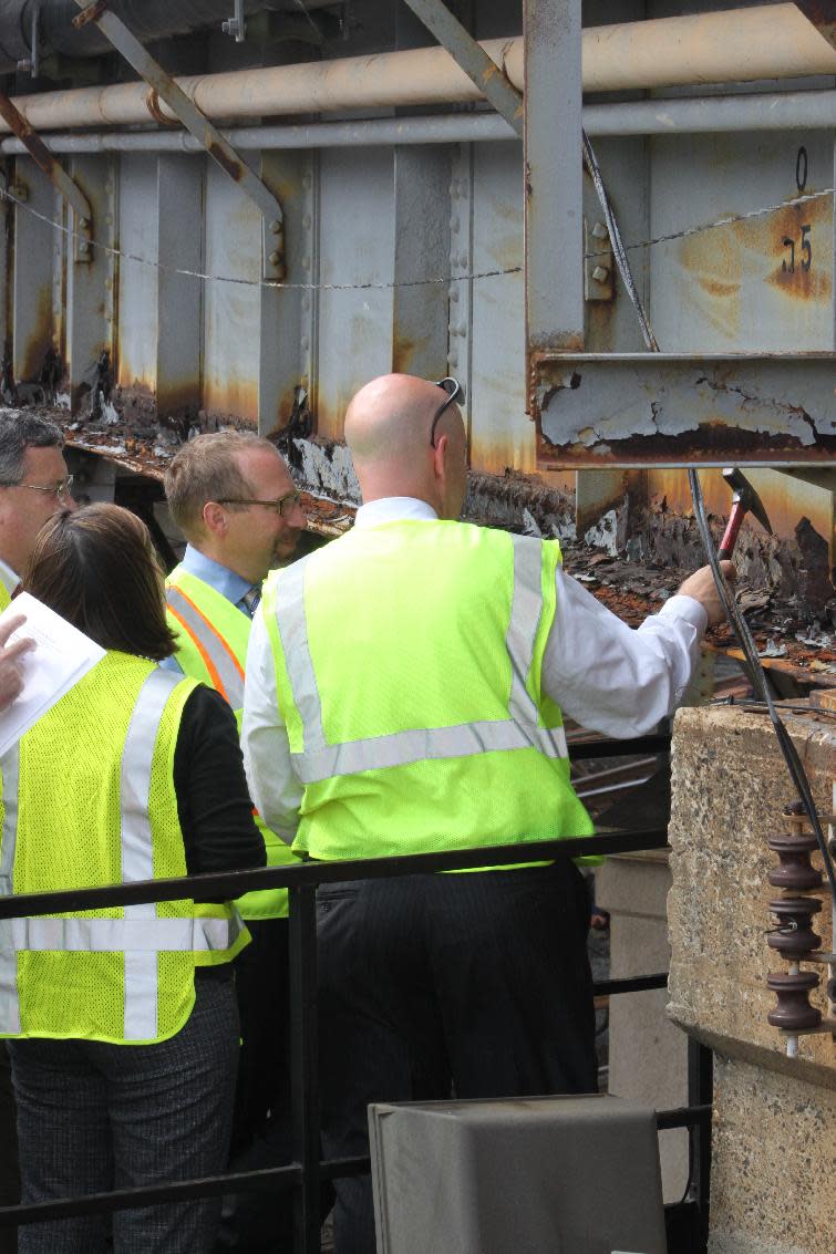 This handout photo, taken in July 2011, provided by the Federal Transit Administration, shows employees of the Southeastern Pennsylvania Transportation Authority show Peter Rogoff, administrator of the Federal Transit Administration, center, corrosion on a Norristown line bridge that’s over 100 years old. The transportation authority is responsible for 347 bridges, some of them dating back to the 1890s. The average age of the bridges is 80 years. Driven by high gas prices and an uncertain economy, Americans are turning to trains and buses to get around in greater numbers than ever before. The aging trains and buses they’re riding, however, face an $80 billion maintenance backlog that jeopardizes service just when it’s most in demand. (AP Photo/Federal Transit Administration) Federal Transit Administration