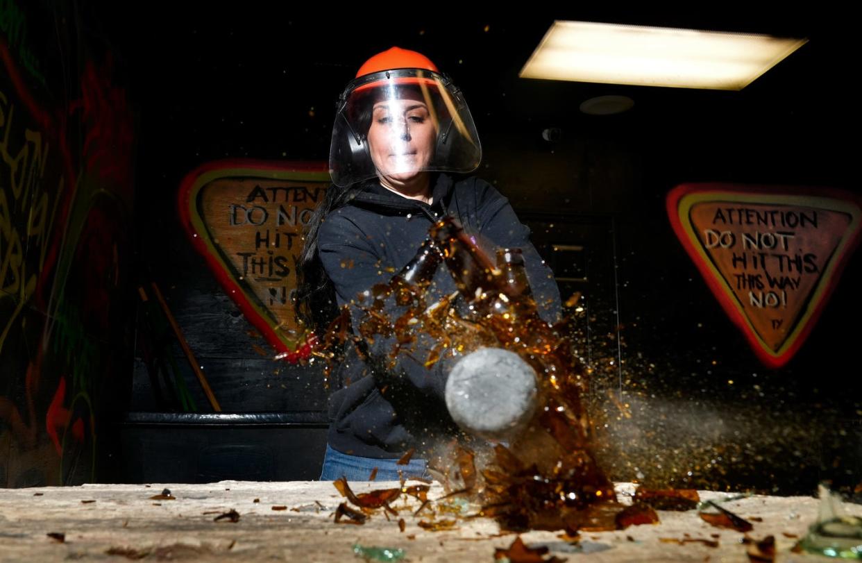 Samantha Rodriguez, owner of Smash ‘n' Splash in West Warwick, makes contact with glass bottles in the rage room.