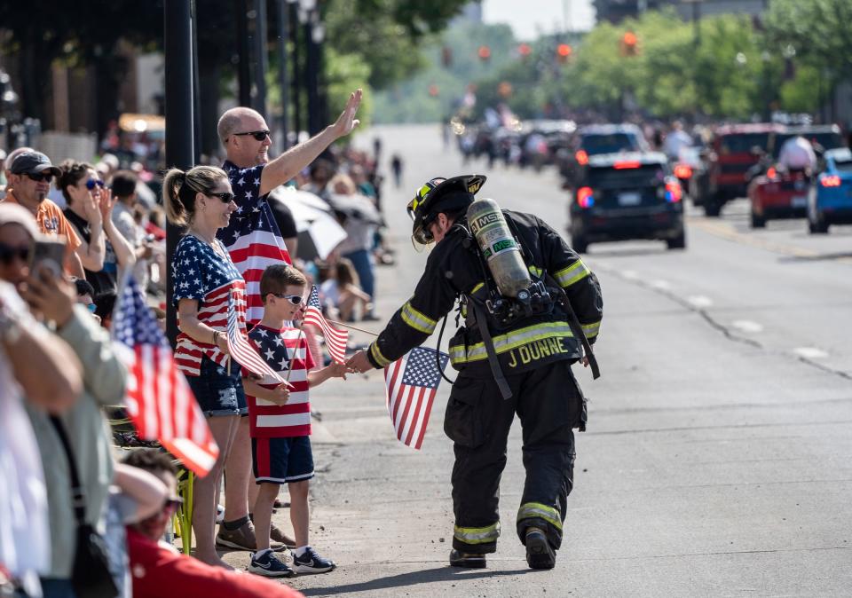 A Dearborn Firefighter passes out candy to people along the route watching during the 97th annual Memorial Day parade along Michigan Avenue in Dearborn on Monday, May 29, 2023.