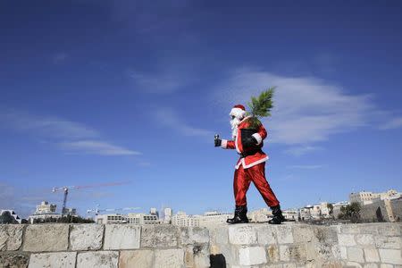 Issa Kassissieh, an Israeli-Arab Christian, wears a Santa Claus costume as he poses for the media in Jerusalem's Old City, during the annual distribution of Christmas trees by the Jerusalem municipality December 22, 2014. REUTERS/Ammar Awad