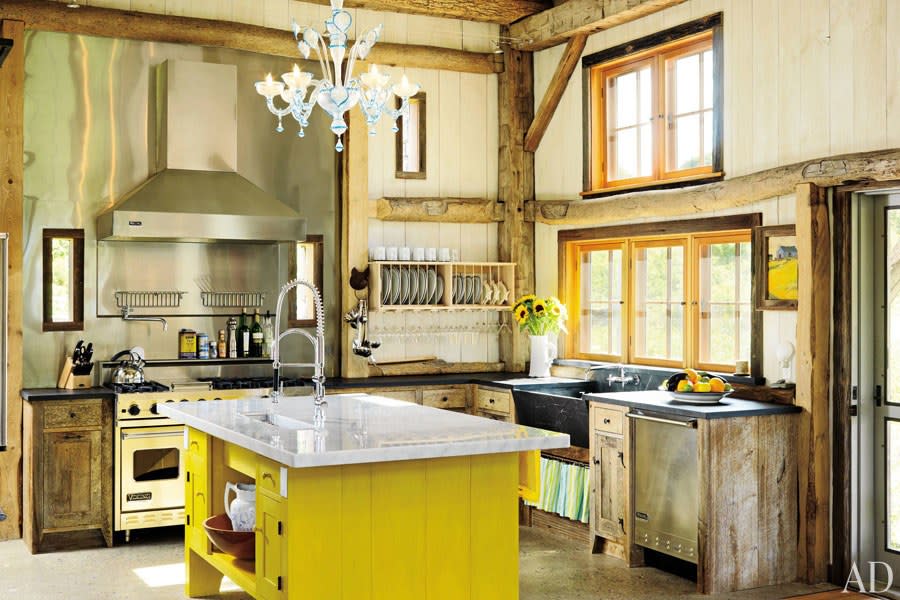 In a 200-year-old barn that she transported to coastal Rhode Island, designer Ellen Denisevich-Grickis created an eclectic kitchen that includes a swish of striped fabric underneath the farmhouse sink.