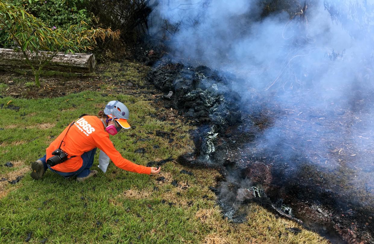 In this file photo from 2018, a geologist collects samples of spatter for laboratory analysis after the eruption of Hawaii's Kilauea volcano near Pahoa following a 5.0-magnitude earthquake, forcing about 1,700 residents to evacuate. The U.S. Geological Survey says nearly 75% of the U.S. is now at risk of experiencing a damaging earthquake.