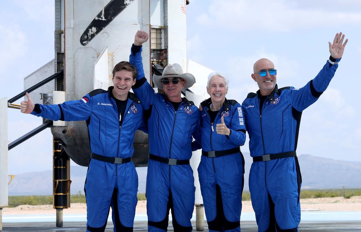 Blue Origin’s New Shepard crew, left, Oliver Daemen, Jeff Bezos, Wally Funk, and Mark Bezos pose for a picture near the booster after flying into space in the Blue Origin New Shepard rocket on July 20 in Van Horn, Texas.