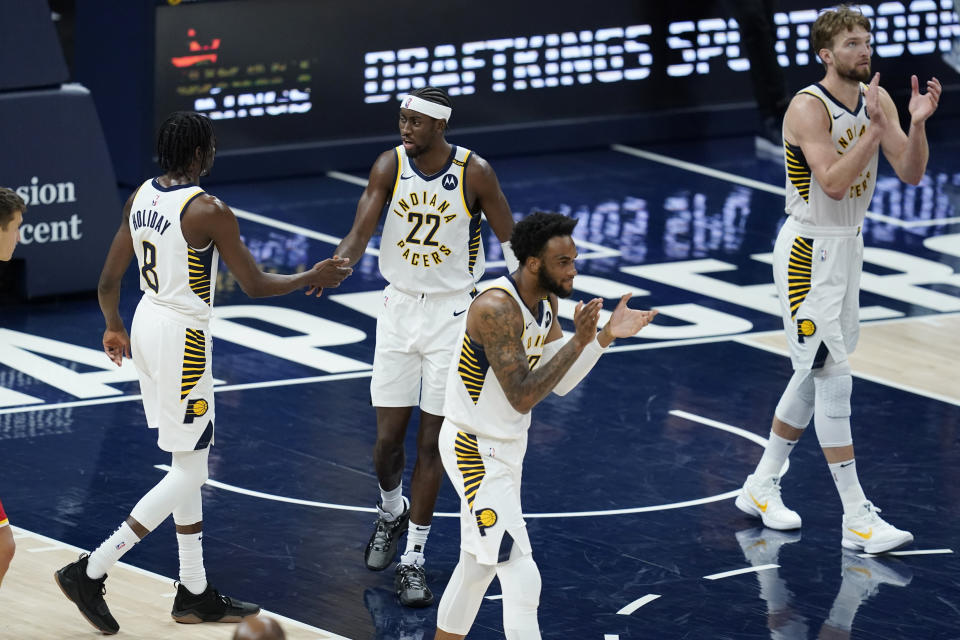 Indiana Pacers' Justin Holiday (8), Caris LeVert (22), Oshae Brissett (12) and Domantas Sabonis (11) celebrate after the Pacers defeated the Atlanta Hawks 133-126 in an NBA basketball game Thursday, May 6, 2021, in Indianapolis. (AP Photo/Darron Cummings)