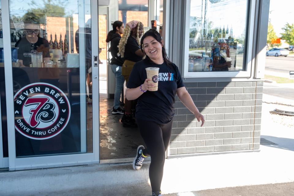 A member of the brew crew brings out an order Wednesday at the grand opening of the Western Street location of 7 Brew in Amarillo.