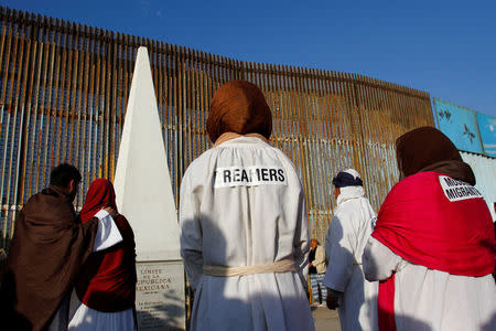 FILE PHOTO: "Dreamers", undocumented immigrants who arrived in the U.S. when they were children, stand near the double steel fence that separates the U.S and Mexico at the border in Tijuana, Mexico, during the annual pre-Christmas "Posada" celebration organised by immigrants and organisations from the U.S. and Mexico, December 16, 2017. REUTERS/ Jorge Duenes/File Photo