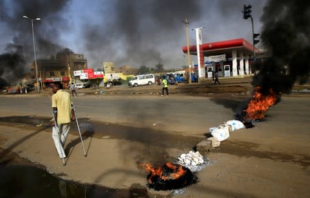 A disabled man walks past a barricade erected by Sudanese protesters along a street, demanding that the country's Transitional Military Council hand over power to civilians, in Khartoum