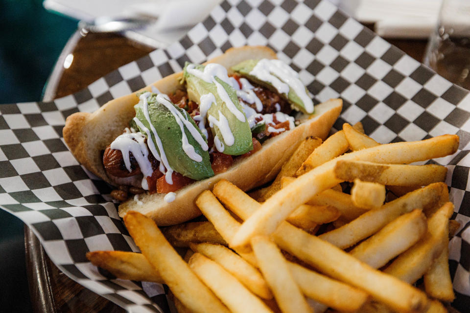 Remi's Arcade & Bistro's Remi Dog features all beef hot dogs with bourbon beans, pico de Gallo, lime crema and avocado.