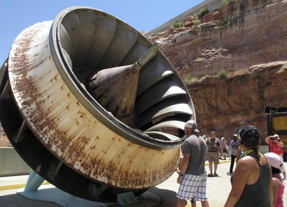 <span class="caption">Tourists look at an old turbine that was replaced at the Glen Canyon Dam.</span> <span class="attribution"><a class="link " href="https://newsroom.ap.org/detail/LakePowellHydropower/22ef0dc7cb274aa5833ccbe041fb0dcd/photo" rel="nofollow noopener" target="_blank" data-ylk="slk:AP Photo/Felicia Fonseca;elm:context_link;itc:0;sec:content-canvas">AP Photo/Felicia Fonseca</a></span>