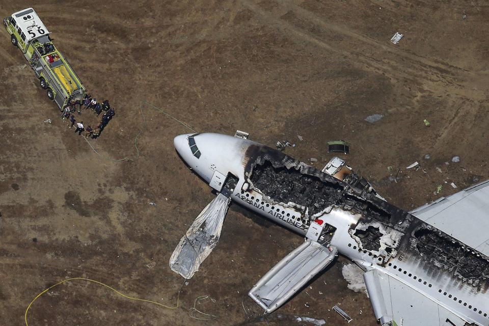 RNPS - PICTURES OF THE YEAR 2013 - Rescue officials stand near an Asiana Airlines Boeing 777 plane after it crashed while landing at San Francisco International Airport in California July 6, 2013. Two people were killed and 130 were hospitalized after the plane crash-landed, San Francisco Fire Department Chief Joanna Hayes-White said. The figures cited by Hayes-White left 69 people still unaccounted for in the accident. The Boeing 777, which had flown from Seoul, South Korea, was carrying 307 people. REUTERS/Jed Jacobsohn (UNITED STATES - Tags: DISASTER TRANSPORT TPX)