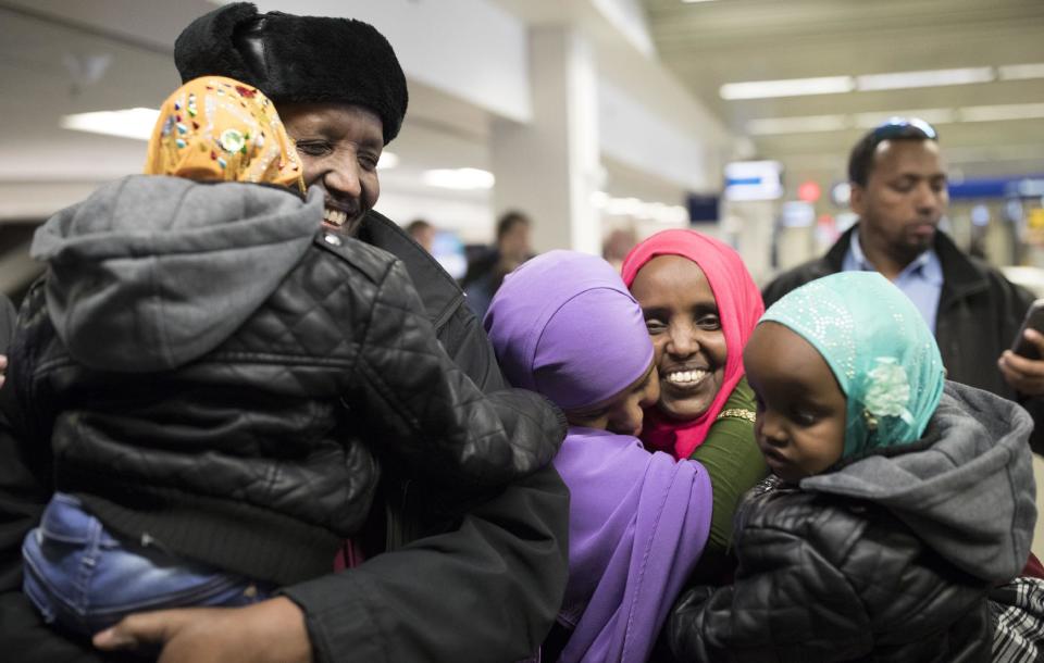 Mohamed lye holds his 4-year-old daughter Nimo as he was reunited with his wife Saido Ahmed Abdille, wearing red scarf, and their other daughter Nafiso, 2, at Minneapolis–Saint Paul International Airport near Bloomington, Minn., after arriving from Amsterdam on Sunday, Feb. 5, 2017. (Jerry Holt/Star Tribune via AP)