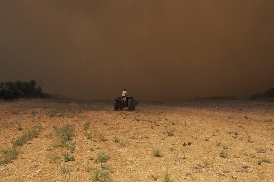 A man drives a tractor as the fire approaches close to Vatontas village on the Aegean Sea island of Evia, Greece, Monday, Aug. 21, 2023. Major wildfires were burning in Greece and on one of Spain's Canary Islands off the African coast Monday, with hot, dry and windy conditions hampering the efforts of hundreds of firefighters battling the blazes, two of which have been burning for several days. (AP Photo/Thodoris Nikolaou)