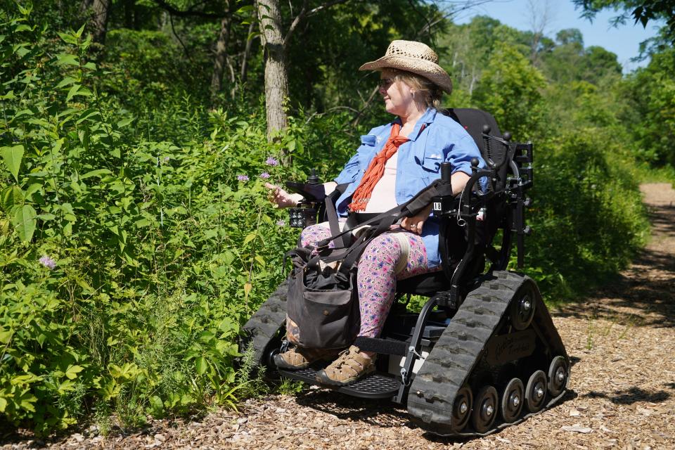 Monica Spaeni, president of Access Ability Wisconsin, views wildflowers while exploring on an outdoor wheelchair on a wood-chip trail at Wehr Nature Center in Franklin. An outdoor wheelchair is available for free public use at Wehr; it may also be towed in a trailer for use elsewhere.
