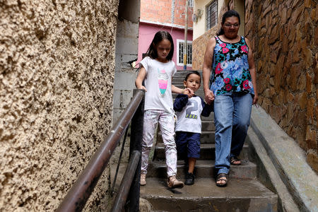 Iris Olivo walks with her grandchildren Ailin Contreras and Andrew Miranda in an alley at the slum of La Vega in Caracas, Venezuela November 16, 2018. Picture taken November 16, 2018. REUTERS/Marco Bello