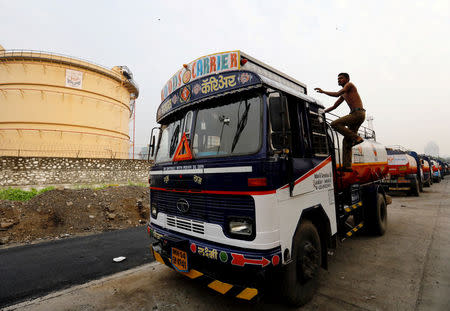 FILE PHOTO: A man climbs an an oil tanker parked outside a fuel depot in Mumbai, October 6, 2017. REUTERS/ Danish Siddiqui/File Photo