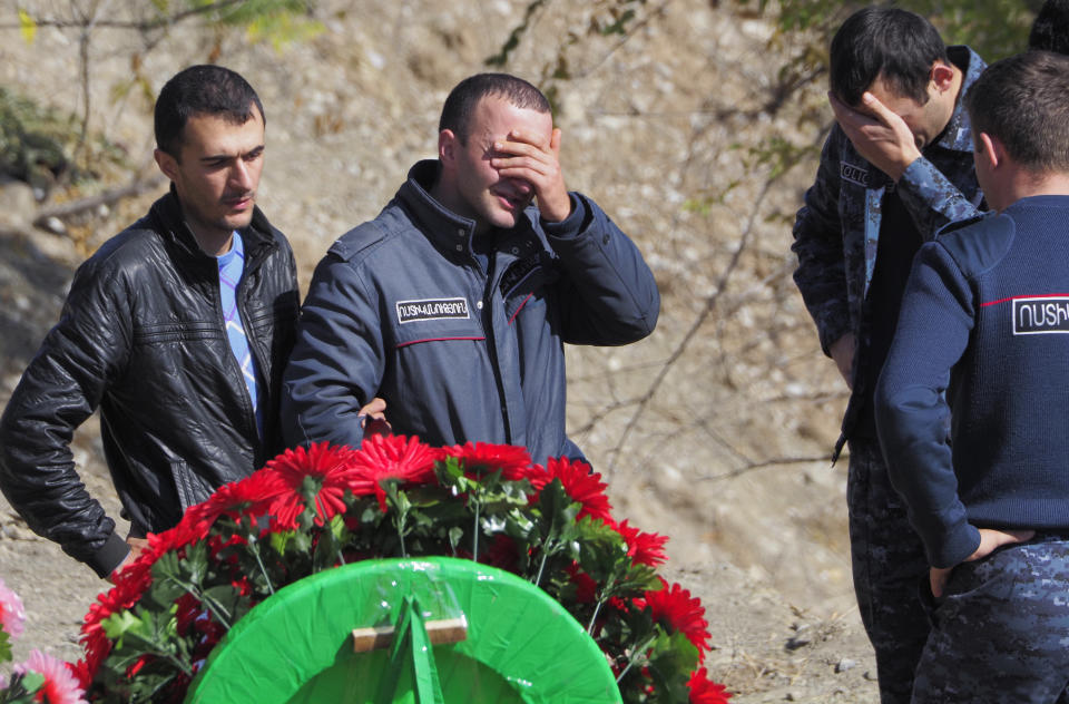 People grieve at the graveside of their relative and friend killed during a military conflict, at a cemetery in Stepanakert, the separatist region of Nagorno-Karabakh, Sunday, Oct. 18, 2020. Armenia and Azerbaijan are trading accusations of violating the new cease-fire in their conflict over the separatist Nagorno-Karabakh territory despite a true announced Saturday that was supposed to take effect at midnight. It is a second attempt to establish a cease-fire in the region since heavy fighting there broke out on Sept. 27. (AP Photo)