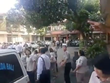 People gathered outside look toward a building as an undersea quake struck south of Bali