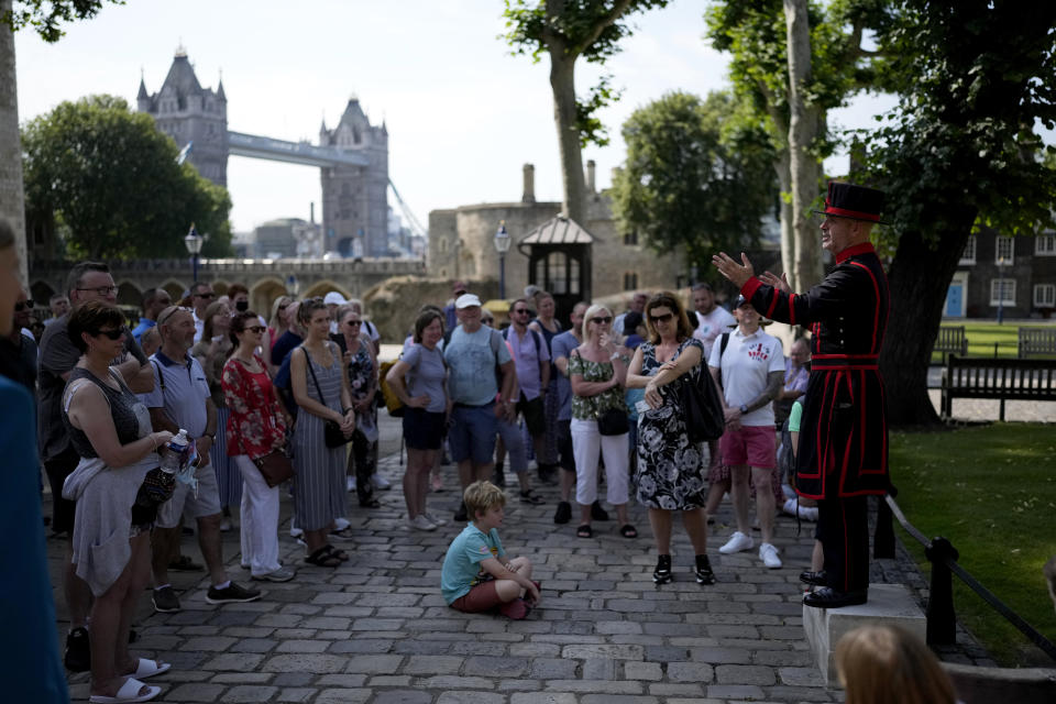 On what some have called "Freedom Day", marking the end of coronavirus restrictions in England, visitors listen as Yeoman Warder Barney Chandler leading the first tour of the Tower of London in 16 months since the start of the coronavirus outbreak, in London, Monday, July 19, 2021. Beginning Monday, face masks will no longer be legally required and with social distancing rules shelved, but mask rules will remain for passengers on the London transport network. (AP Photo/Matt Dunham)