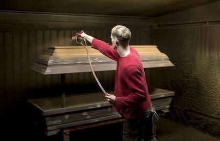 A worker paints a coffin in Berlin, December 1, 2014. REUTERS/Axel Schmidt