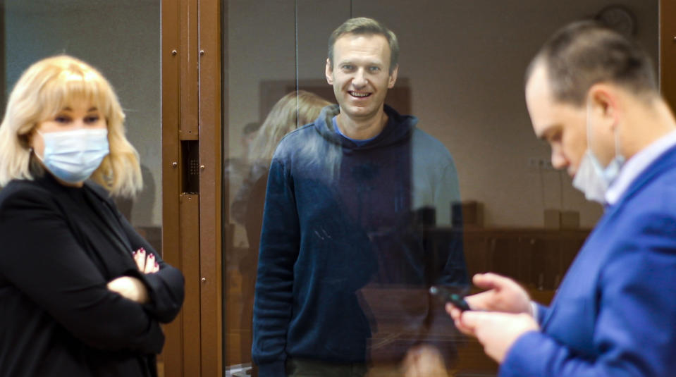 FILE - In this photo taken from a footage provided by the Babuskinsky District Court on Feb. 16, 2021, Russian opposition leader Alexei Navalny, center smiles as he talks with his lawyers Olga Mikhailova, left, and Vadim Kobzev during a hearing on his charges for defamation in the Babuskinsky District Court in Moscow, Russia. Mikhailova, a lawyer for imprisoned opposition leader Alexei Navalny said Tuesday that the authorities charged her with participating in an extremist group in absentia. (Babuskinsky District Court Press Service via AP, File)