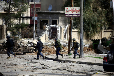 Federal police members carry their weapons as they attempt to break into the Old City during a battle against Islamic State militants, in Mosul. REUTERS/Thaier Al-Sudani