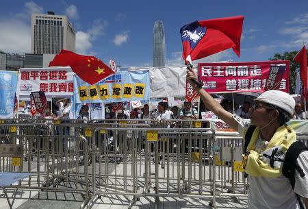 A pro-democracy protester (R) carrying a Taiwan flag demonstrates in front of pro-China supporters waving a Chinese national flag outside Legislative Council in Hong Kong, China June 17, 2015. REUTERS/Bobby Yip