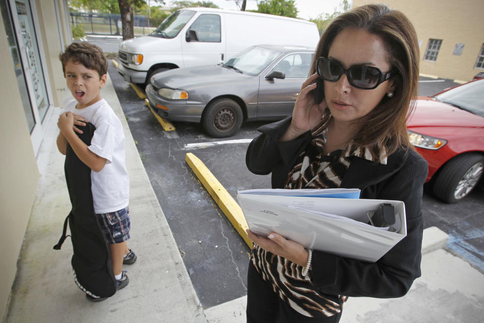 Businesswoman Irela Bague multitasks as she drops her son, Alberto, at his father’s office in Miami. (Photo: Al Diaz/Miami Herald/MCT via Getty Images)