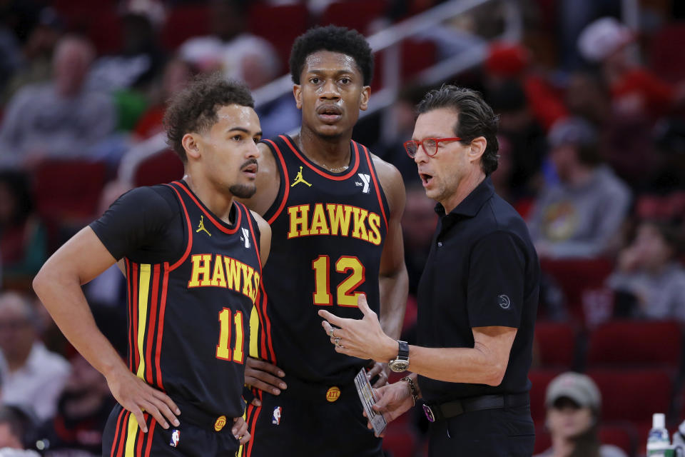 Atlanta Hawks guard Trae Young (11) and forward De'Andre Hunter (12) talk with coach Quin Snyder during a timeout in the first half of an NBA basketball game against the Houston Rockets on Wednesday, Dec. 20, 2023, in Houston. (AP Photo/Michael Wyke)