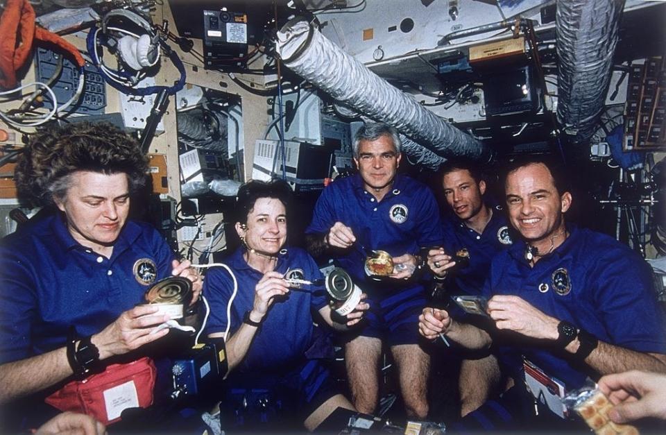 Astronauts eating in a spacecraft