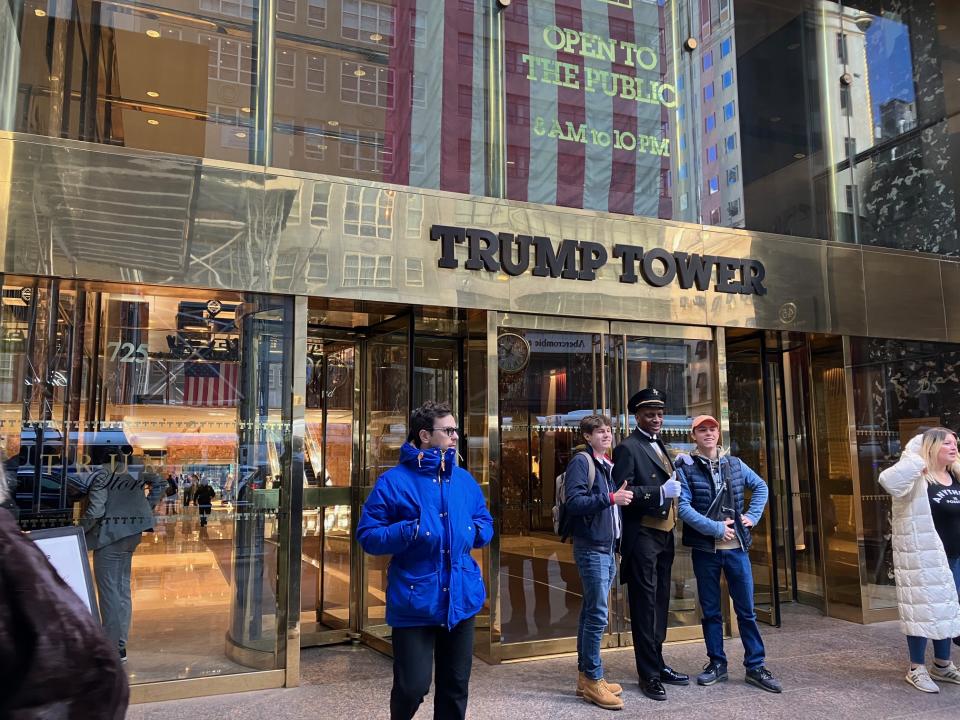 A security guard poses with tourists and gives a thumbs-up.