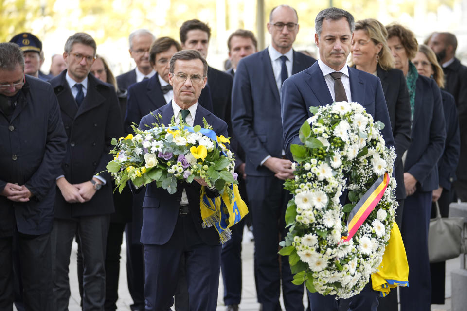 Sweden's Prime Minister Ulf Kristersson, center left, and Belgium's Prime Minister Alexander De Croo, center right, carry floral tributes during a commemoration for the victims of a shooting in the center of Brussels, Wednesday, Oct. 18, 2023. Police in Belgium on Tuesday shot dead a suspected Tunisian extremist accused of killing two Swedish soccer fans in a brazen attack on a Brussels street. (AP Photo/Martin Meissner)