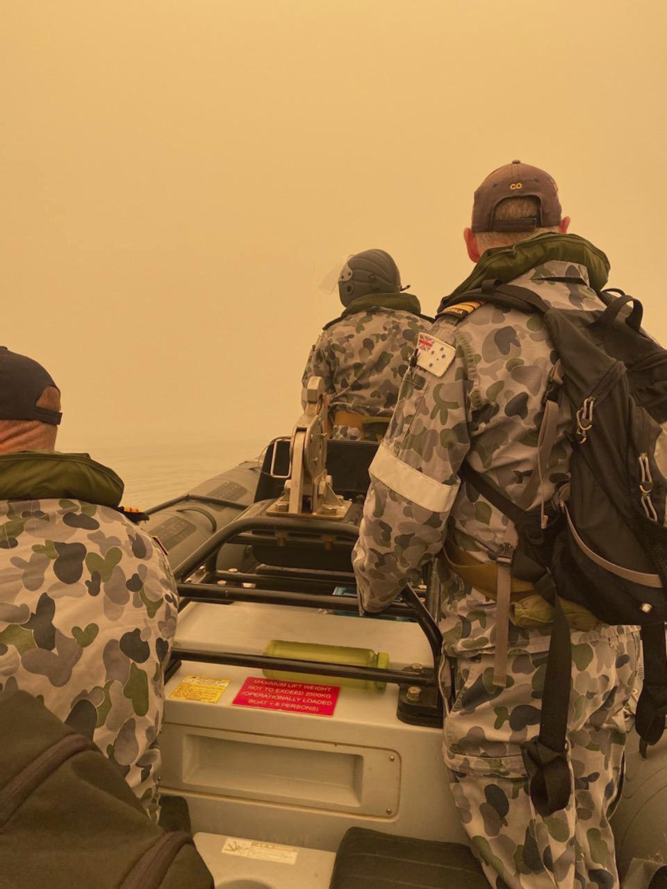 In this photo provided by the Australian Defence Force, a tender from HMAS Choules motors through smoke haze off the coast of Mallacoota, Australia, Thursday, Jan. 2, 2020. The Australian Defence Force is moving naval assets to Mallacoota on a supply mission that would last two weeks and helicopters would also fly in more firefighters since roads were inaccessible due to wildfires. (Australian Defence Force via AP)