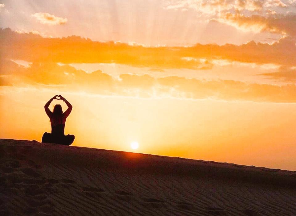 Kate Boardman sitting on a sand dune in Oman.