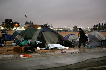 A man walks through the rain to a tent near a Walmart in Chico, California, U.S. November 21, 2018. REUTERS/Elijah Nouvelage