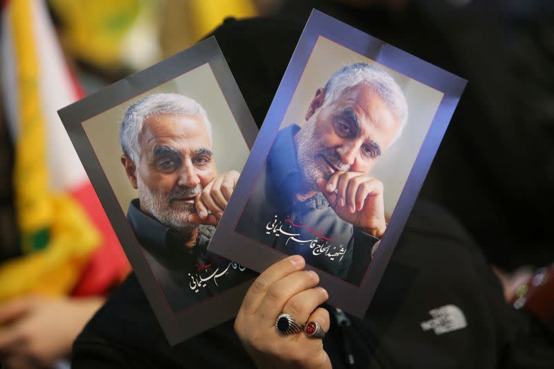 A supporter of Lebanon's Hezbollah leader Sayyed Hassan Nasrallah carries pictures of the late Iran's Quds Force top commander Qassem Soleimani during a rally commemorating in Beirut's southern suburbs