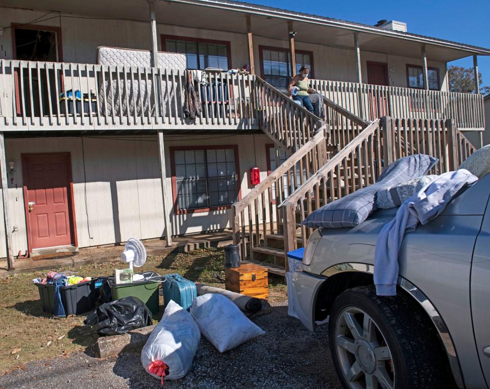 A friend of an Aspen Village Apartments resident helps salvage items from an upstairs apartment destroyed by fire Wednesday.