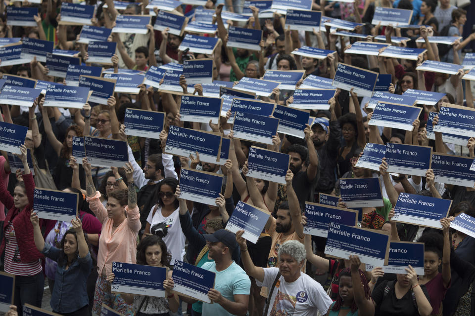 People hold street signs honoring slain councilwoman Marielle Franco as they mark the 7th month since her murder in Rio de Janeiro, Brazil, Sunday, Oct. 14, 2018. Franco supporters distributed a thousand street signs in memory of her after a video on social media showed one being destroyed by two politicians with the right wing Social Liberal Party. (AP Photo/Leo Correa)