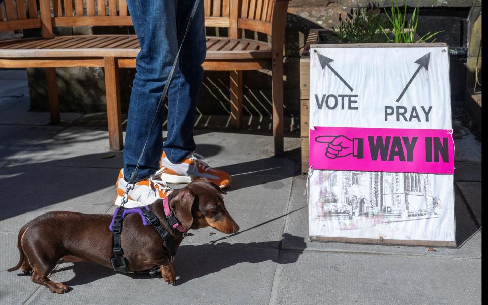 A person and a dog wait outside St James' Church voting station in Edinburgh, Scotland, on July 4, 2024. REUTERS/Lesley Martin