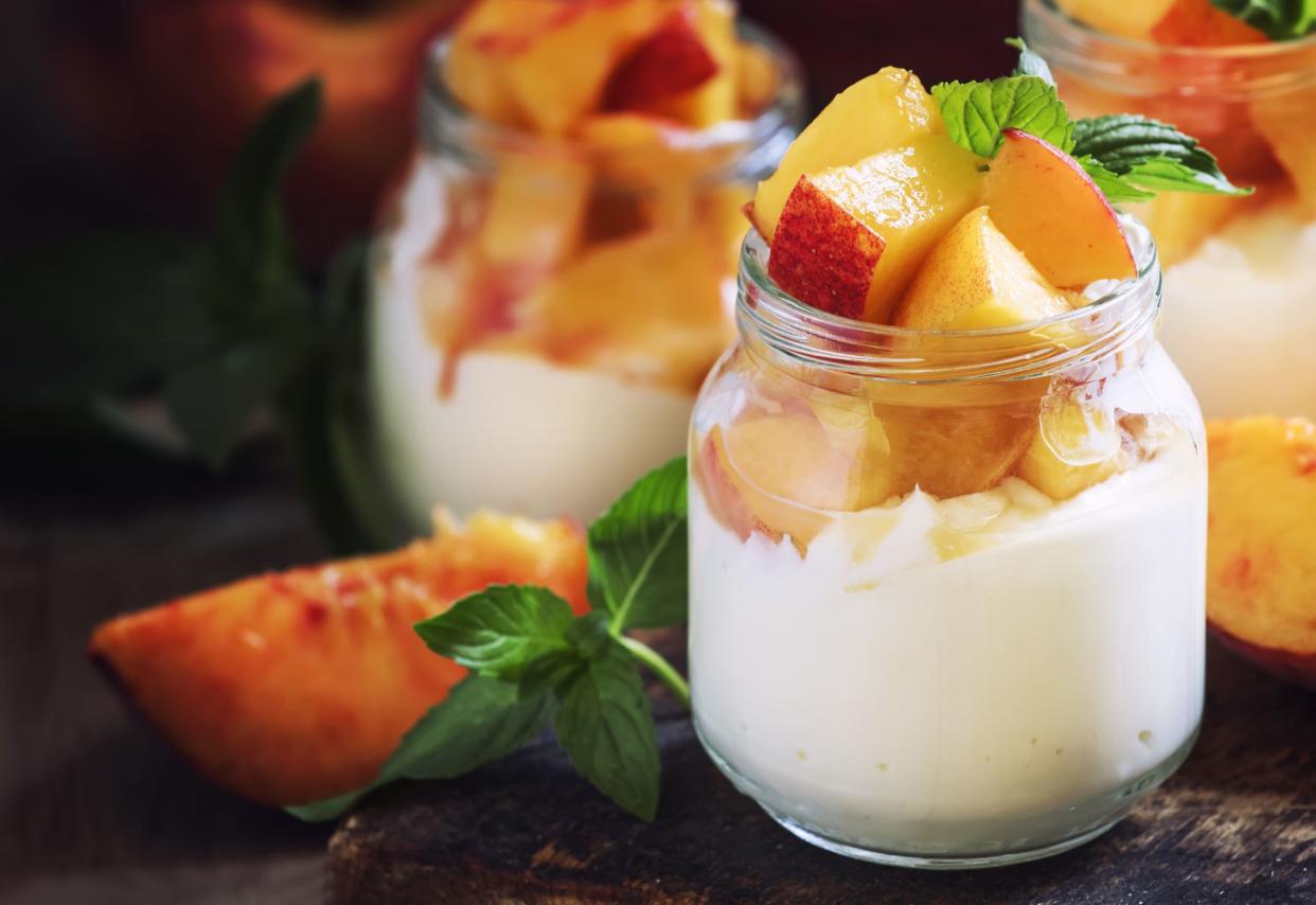 Dessert with sweet peaches, cottage cheese and whipped cream, served in glass jars, vintage wooden background, selective focus