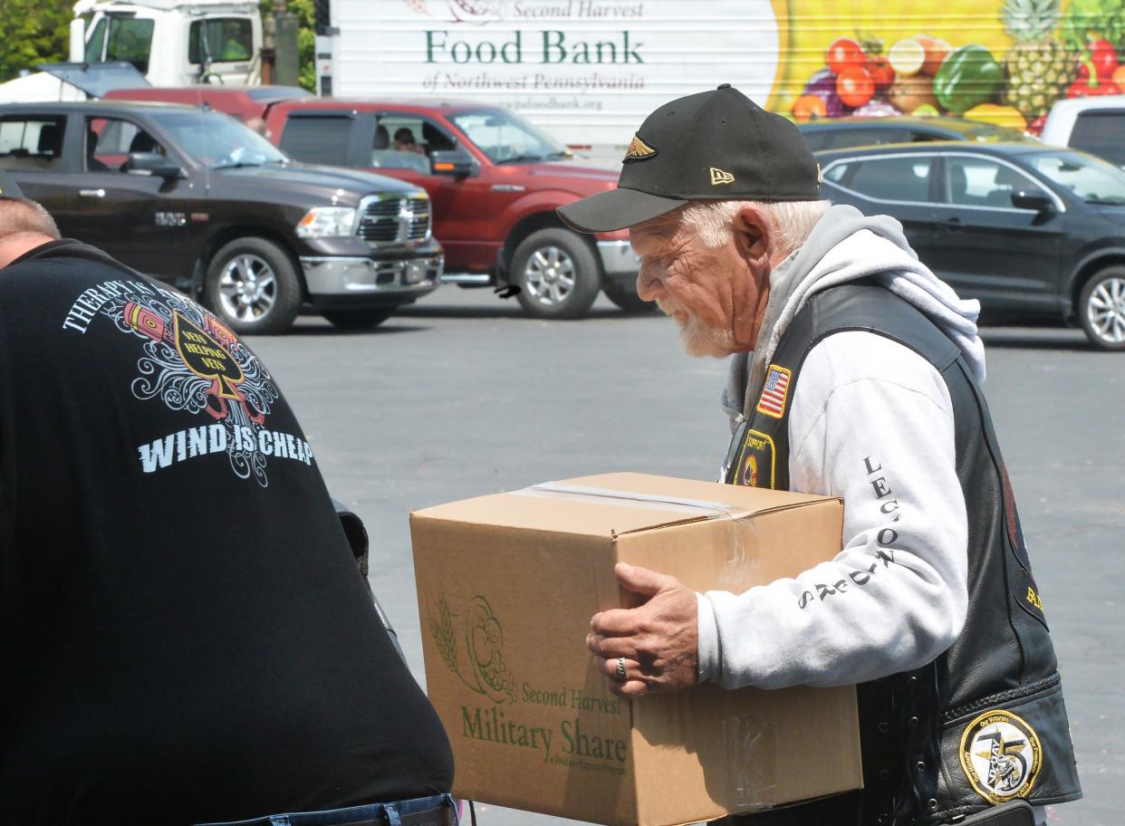 U.S. military veteran Dale Snyder helps load food into the cars of military veterans as part of a Military Share food distribution at the Second Harvest Food Bank in Erie on May of 2023.