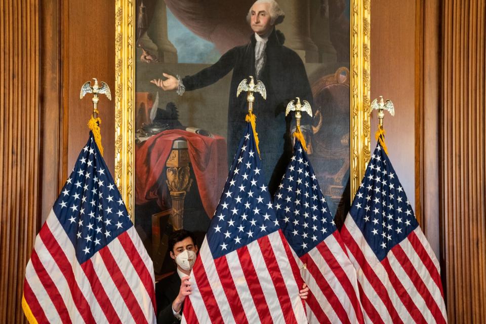 A congressional staffer adjusts several flags