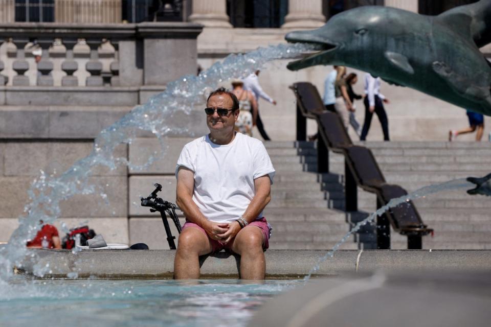 A man cools off in a fountain during the hot weather in London (REUTERS)
