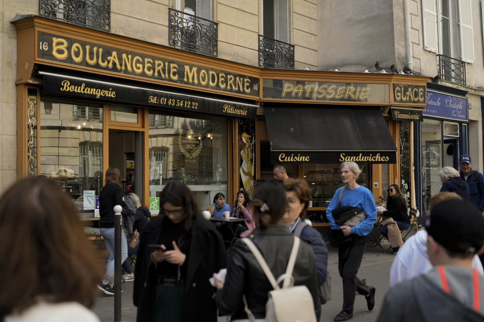 People walk past the "Modern bakery", Place de d'Estrapade, in Paris, Wednesday, April 19, 2023. The immense success of the Netflix series "Emily in Paris" has transformed a quiet, untouched square in the French capital into a tourist magnet. (AP Photo/Thibault Camus)