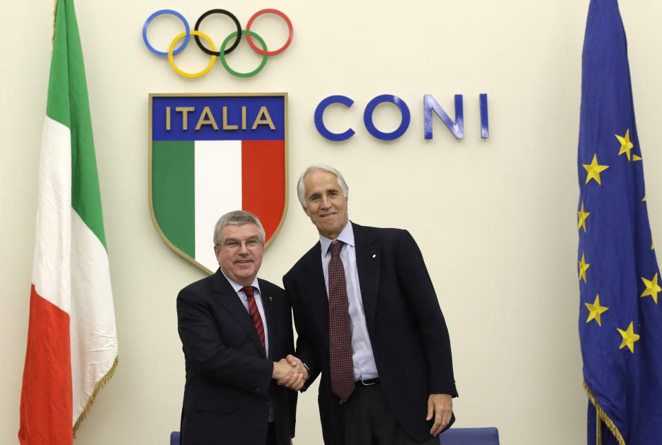 FILE - In this Thursday, Nov. 8, 2018 filer, International Olympic Committee President Thomas Bach, left, and Italian Olympic Committee President Giovanni Malago', shakes hands for photographers at the end of a press conference in Rome. Enjoying its status of the leading contender to host the 2026 Winter Olympics, the Milan-Cortina d'Ampezzo bid has received another boost with a funding promise from the Italian government. Interior Minister Matteo Salvini says that if "private funding isn't enough, we'll make the final push" to cover the remaining costs. Salvini's announcement in an interview with Leggo.it signals a shift after Deputy Premier Luigi Di Maio said last month that the government would send a letter of support for the bid to the International Olympic Committee "but as government we won't provide 1 euro, neither for direct nor indirect costs." (AP Photo/Alessandra Tarantino, File)