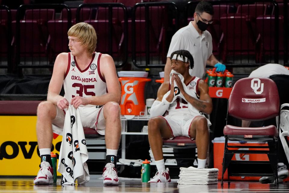 Brady Manek, left, and Alondes Williams look on from Oklahoma’s socially distanced bench area during the Sooners’ blowout of UTSA in December 2020.